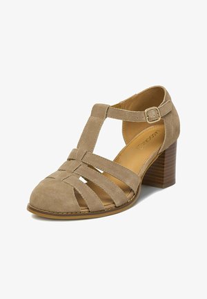 Dámská béžová semišová sandála s pevnou podrážkou, uzavřenou špičkou s T-páskem a několika překříženými pásky, a nastavitelnou přezkou.