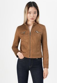 Veste en daim synthétique brun avec fermeture éclair à l'avant, deux zips sur la poitrine et un col haut. Présente un design ajusté et des manches longues.