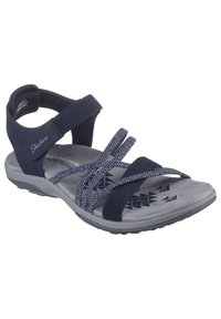 Sandal blu navy con cinghie in tessuto, soletta grigia testurizzata e design imbottito. Presenta motivi geometrici sulla soletta. Suola in gomma.
