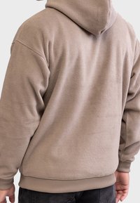 Fleece hoodie i taupe med en tekstureret overflade, afslappet pasform og ribbede manchetter og kant. Har en rummelig hætte for ekstra komfort.