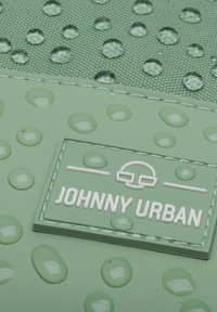 Zöld vízálló táska texturált felülettel, vízcseppekkel és egy fehér logóval, amelyen a "JOHNNY URBAN" felirat található.