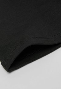 Czarny bawełniany t-shirt z wykończeniem o gładkiej fakturze i wzmocnionymi szwami. Zaokrąglone brzegi oraz subtelny prążkowany detal wzdłuż dekoltu.