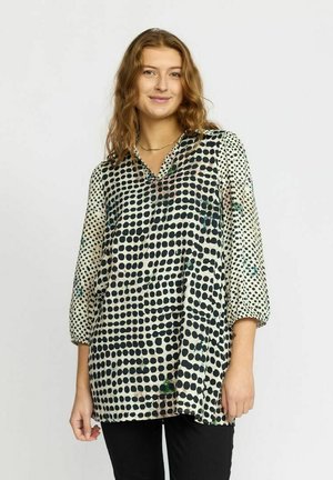 Gennemsigtig bluse med kravehals, udstyret med store sorte polka prikker på en cremefarvet baggrund, 3/4 ærmer og en løs pasform.