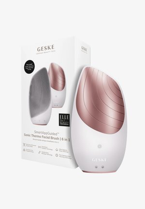 Sonic Thermo Facial Brush med en vit kropp, detaljer i roséguld, en texturerad yta av silikon och en strömlinjeformad design. Förpackning ingår.