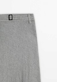 Jupe en tissu gris texturé avec ceinture, passants de ceinture et petite boucle rectangulaire noire sur fond blanc.