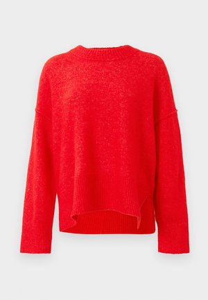 Červený pletený svetr s podloženým kulatým výstřihem, volným střihem a sníženými rameny. Má vysoký a nízký lem a texturovanou tkaninu.