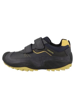 Chaussure de sport décontractée noire et jaune avec deux bandes velcro et semelle en caoutchouc texturée, vue latérale montrant la marque Geox.