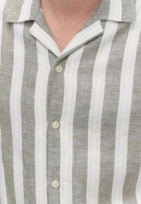 Szara i biała w paski koszula z krótkim rękawem z kołnierzykiem, z dwoma jasnymi guzikami i teksturowanym materiałem.