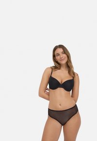 Sostén negro con bordes festoneados y tela texturizada, combinado con bragas negras de malla de talle alto que presentan un patrón de diamantes.