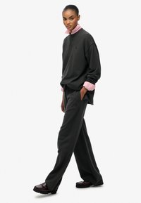 Mørkegråt sæt med sweatshirt og bukser i afslappet pasform. Lyserød skjorte med krave under, med ribstrikkede manchetter, og sneakers med tekstureret stof.