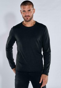 Black long-sleeve shirt made of smooth material, featuring a round neckline and fitted design. Subtle stitching detail along the hems.