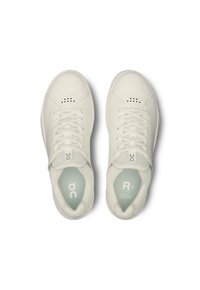 Scarpe da ginnastica bianche con una tomaia in pelle liscia, chiusura con lacci, dettagli perforati vicino alla punta e una soletta di colore azzurro chiaro.