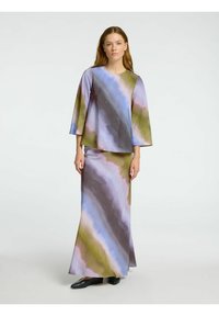 Zweiteiliges Outfit mit einem fließenden, mehrfarbigen Oberteil und einem passenden langen Rock mit einem Aquarell-Muster in Blau-, Grün- und Lilatönen.