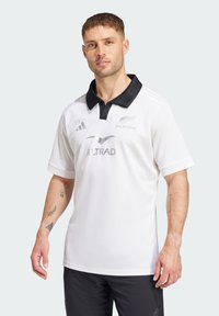 Hvid rugbytrøje med sort krave, udstyret med sølvlogoer for "ALL BLACKS" og "ALTRAD", lavet af letvægtsstof, kortærmet.