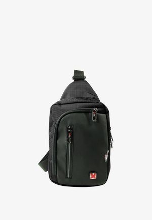 Sling rugzak in donkergroen en zwart stof, met meerdere ritscompartimenten, een verstelbare band en logo detail.