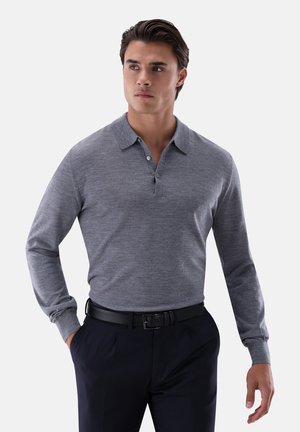 Graues langärmeliges Poloshirt mit Kragen und zweiknöpfiger Knopfleiste. Glatte Textur, figurbetontes Design, kombiniert mit dunkler Hose und schwarzem Gürtel.