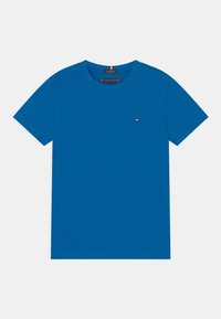 Camiseta de cuello redondo de manga corta en color azul con pequeño logo de bandera de Tommy Hilfiger en el lado izquierdo del pecho y etiqueta de algodón orgánico en el cuello.