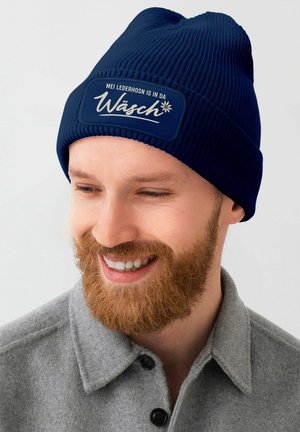 Navy knitted beanie with a ribbed texture and a contrasting patch featuring white text and a floral design.