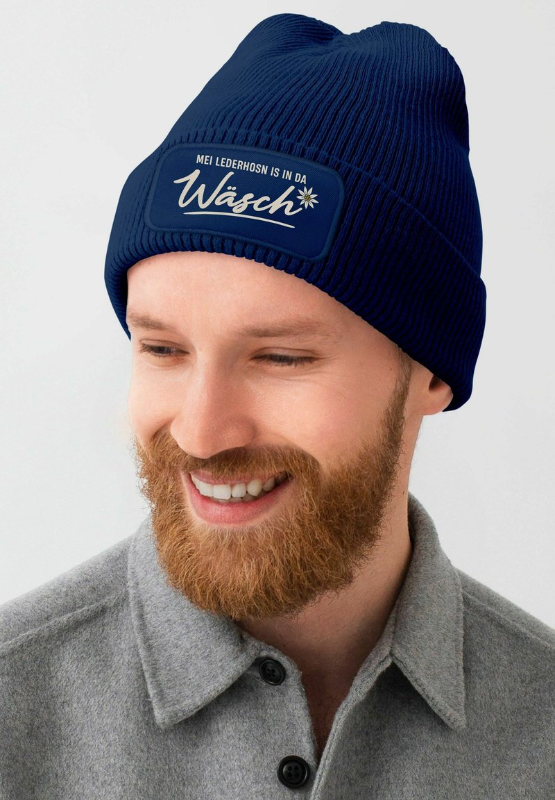 Navy knitted beanie with a ribbed texture and a contrasting patch featuring white text and a floral design.