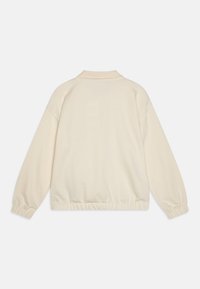 Κρεμ σε χρώμα, ελαφρύ φούτερ με κολάρο, ελαστικούς καρπούς και στριμωγμένο τελείωμα για άνετη εφαρμογή. Μαλακή, λεία υφή.