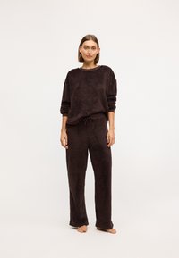 Dunkelbraunes, flauschiges Loungewear-Set, bestehend aus einem langärmeligen Rundhalsausschnitt-Pullover und lockeren Hosen mit verstellbarem Kordelzug.