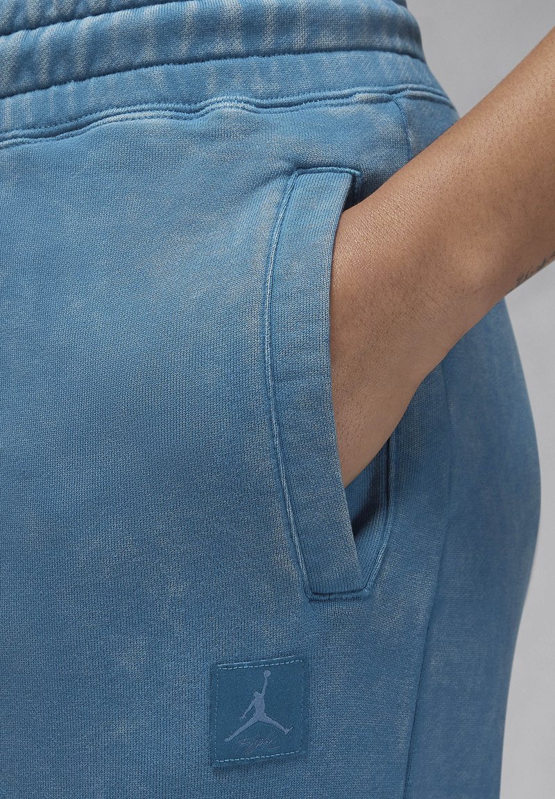 Pantalons de survêtement bleus en tissu doux, dotés d'une poche latérale et d'un patch texturé avec un logo Jumpman.