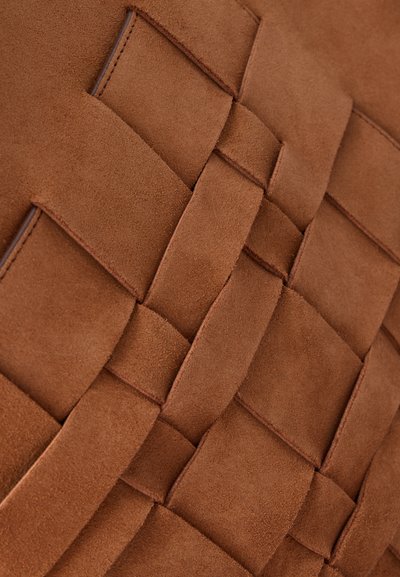 Gros plan de bandes de cuir suédé marron tissées formant un motif texturé et entrelacé.