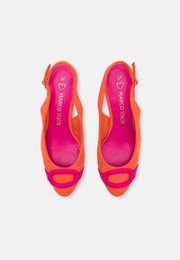 Slingback-kengät kirkkaan oranssista mokasta, jossa on vaaleanpunainen korostushihna ja neliönmuotoinen solki. Sisus on varustettu rohkealla vaaleanpunaisella vuorilla ja brändin nimellä.