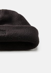 Viseira preta em fleece com uma superfície texturizada, apresentando um punho dobrado e um detalhe de logotipo discreto. Material macio proporciona calor e conforto.