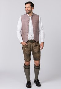 Brown leather shorts with decorative stitching, light pink patterned vest, white shirt, and knee-high knitted gray socks. Black shoes.