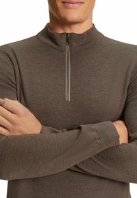 Brauner Zip-Top mit hohem Kragen, aus strukturiertem Strickstoff. Verfügt über lange Ärmel und einen Reißverschluss in halber Länge auf der Vorderseite.