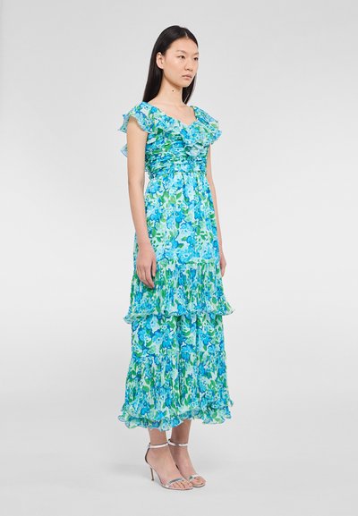 Robe à imprimé floral avec différentes nuances de bleu et de vert, manches volantes et couches superposées, fabriquée en tissu léger et fluide.