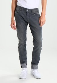 Jeans de algodón gris con mezcla, de corte ajustado, que cuentan con bolsillos frontales, cierre de botón y puños doblados para revelar una tela de contraste.