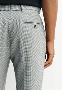 Gray houndstooth pattern trousers with a smooth texture, featuring a single back pocket with a button, tailored fit, and belt loops.