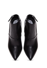 Botines de cuero negro hasta el tobillo con punteras puntiagudas y cremalleras laterales, que presentan una textura suave y un diseño elegante.