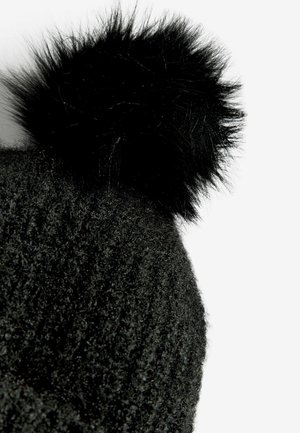 Čierna pletená čiapka s jemným, textúrovaným povrchom a nadýchaným čiernym brmbolcom na vrchu. Detailný pohľad zdôrazňujúci materiál a dizajn.