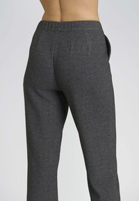 Pantaloni grigi con texture, dotati di vita piatta e tasche laterali, con una vestibilità su misura che si estende dalla vita alla caviglia.