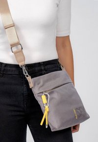 Borsa a tracolla in tessuto grigio testurizzato con dettagli gialli e moschettone. Fascia beige regolabile e tasca frontale con zip.