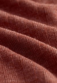 Tissu texturé brun avec un motif à nervures verticales, présentant des fibres douces créant une apparence douce et chaleureuse.