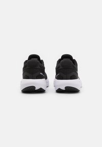 Zapatillas deportivas negras con parte superior de tela de malla, collar acolchado y suela blanca. Presentan acentos texturizados y un diseño de talón reforzado.