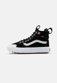 Černé semišové tenisky v vysokém provedení s bílými akcenty, gumovou podešví a polstrovaným límcem s vyztuženými očky a štítkem s logem.