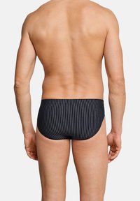 Slip da nuoto neri con strisce verticali, caratterizzati da una texture liscia e una vita elasticizzata. Il design è semplice e aderente.