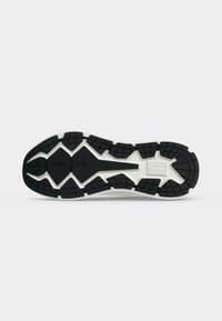 Semelle d'une chaussure blanche avec motif en caoutchouc noir et grips texturés pour une meilleure stabilité et durabilité.