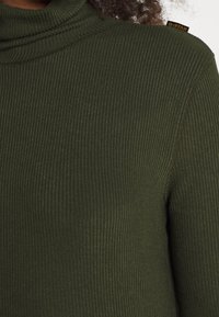 Top a collo di cravatta a coste verde scuro con una texture morbida, caratterizzato da un piccolo tag con logo G-Star nero sulla cucitura della spalla.