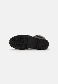 Suela de bota de goma negra con un patrón de relieve texturizado para agarre. Presenta una base plana y una zona de punta reforzada para mayor durabilidad.