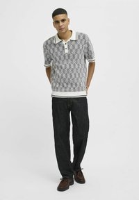 Pelēka rakstaina polo krekla ar īsām piedurknēm un baltu apkakli. Apvienots ar tumšiem džinsiem un brūnām šņorējamām kurpēm.