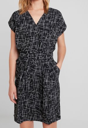 Schwarzes Kleid mit weißen abstrakten Linien, kurzen Ärmeln, V-Ausschnitt und elastischem Taillenbund. Verfügt über seitliche Taschen und einen lockeren Schnitt.