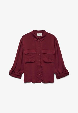 Camisa burdeos de manga larga con cuello, que presenta dos bolsillos frontales y mangas enrolladas, exhibida sobre un fondo blanco.