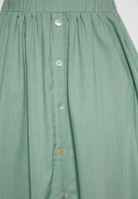 Fustă midi verde dintr-un material ușor, cu talie plisată și cinci nasturi de culoare argintie pe față pentru închidere.
