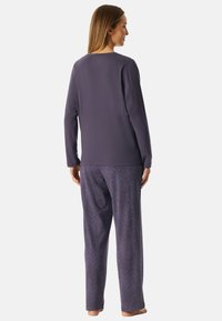 Lila Langarmshirt und gemusterte Schlafanzughose mit wellenförmigem Design. Der Stoff hat eine weiche Textur für Komfort.